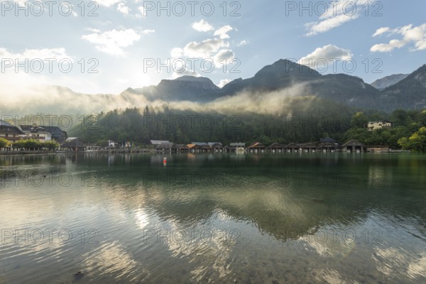 Mystical morning at Königssee in Schönau with boathouses. Sunrise and beautiful wafts of mist over the Königssee in the basin