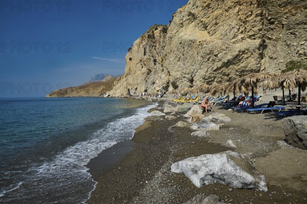 Calm beach with gentle waves in front of high cliffs and clear sea, Embros Thermen, Kos, Dodecanese, Greek Islands, Greece