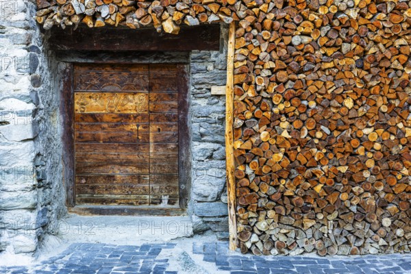 Entrance to a wine cellar framed by firewood logs, historic village centre, Grimentz, Val d'Anniviers, Valais Alps, Canton Valais, Switzerland