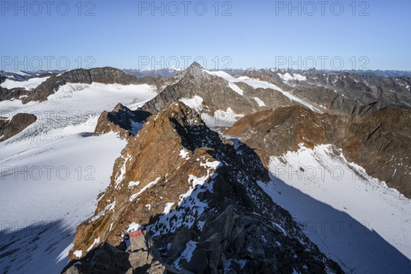 Narrow rocky ridge on the Wilder Freiger summit, picturesque high mountain landscape with snow, view of Übeltalferner glacier and rocky Wilder Pfaff mountain summit, Stubai Alps, South Tyrol, Italy