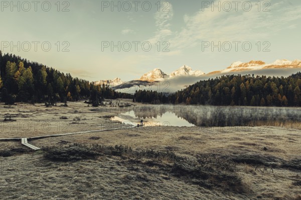Lake Staz near Sankt Moritz in the Engadin in Switzerland. Morning atmosphere with fog in autumn. Water reflection and snow-covered mountains in the background