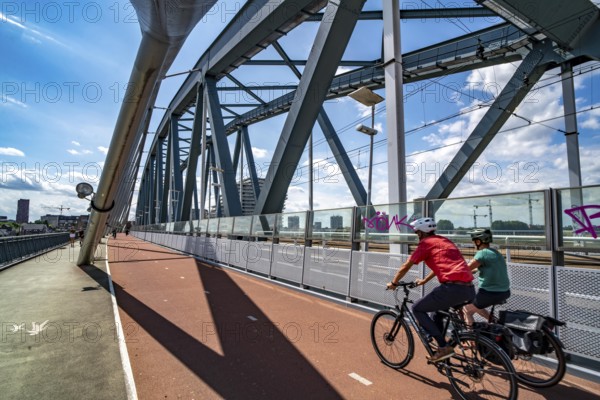 Cycle and pedestrian bridge Snelbinder Brug, over the river Waal near Nijmegen, was added to the existing railway bridge, fast cycle path connection from the city centre of Nijmegen and the new housing estates in the Waalsprong district, Netherlands