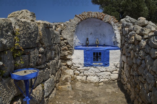 Stone chapel with blue window amidst ancient ruins, surrounded by natural walls and a deep blue sky, Artemis Temple, Artemis, Diana, goddess of the hunt, altar. Church, tower, near the airport in the north of the island, Leros, Dodecanese, Greek Islands, Greece