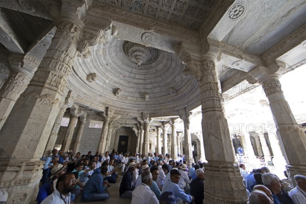 Indian men praying between the white marble pillars in the Adinath temple in Ranakpur, Jain temple, Rajasthan, India