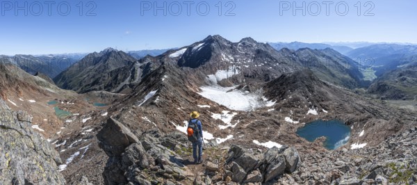 Mountain panorama, mountaineer in rocky high mountain landscape at the Rotgratscharte, view of mountain landscape with blue glacier lake, descent from the summit Roter Grat, Stubai Alps, South Tyrol, Italy