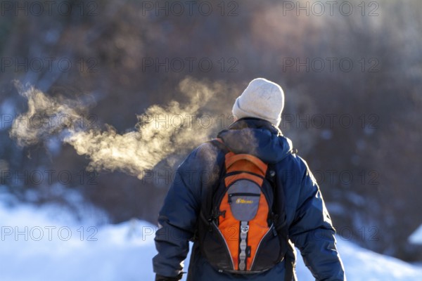 Person walking in very cold weather, Visual effect of the steam seen when exhaling in cold weather. City of Montreal, Province of Quebec, Canada, North America