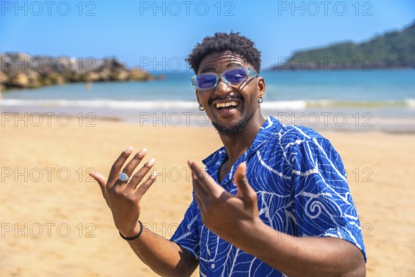 Young man enjoying summer vacation on a tropical beach, smiling widely and gesturing joyfully while soaking up the sun and ocean breeze