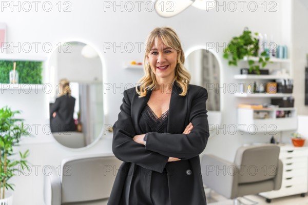 Beautician smiling confidently with crossed arms, posing in her modern beauty salon, engaging with the camera in a warm portrait