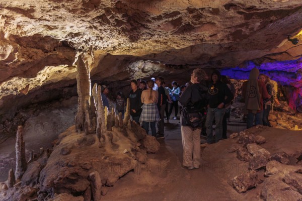 Tourists walking past limestone rock formations in a cave at Florida Caverns State Park in the Florida panhandle near Marianna
