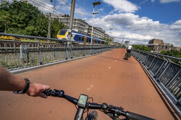 Ride over the Snelbinder Brug bicycle and pedestrian bridge, over the river Waal near Nijmegen, was built on the existing railway bridge, fast cycle path connection from the city centre of Nijmegen and the new housing estates in the Waalsprong district, Netherlands