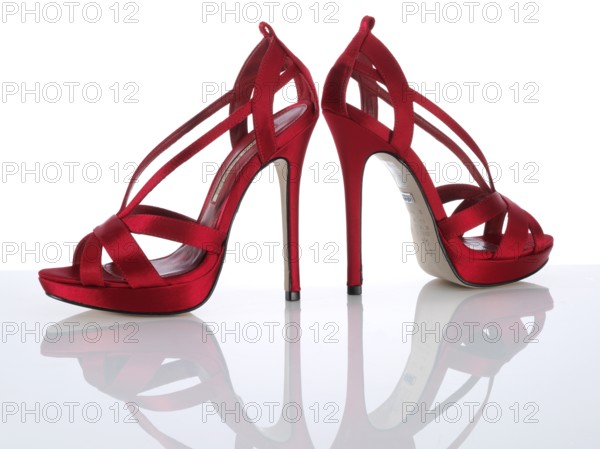 A pair of red ladies pumps, high heels, in front of a white background, studio shot