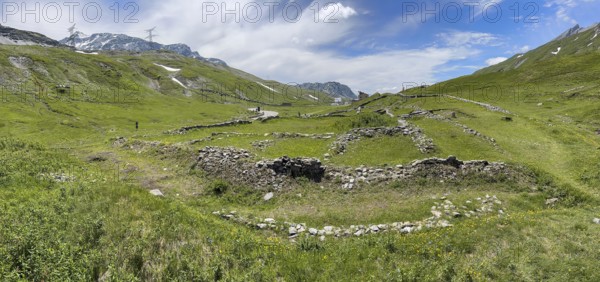 Panoramic photo of foundation walls ruins of 2000 years old historical ancient Roman hostel Mansio on top of Alpine pass Colle del Piccolo San Bernardo between modern pass road and old mule track, Col du Petit Saint Bernard Little Saint Bernard Pass in Alps, Valle d'Aosta region, Italy
