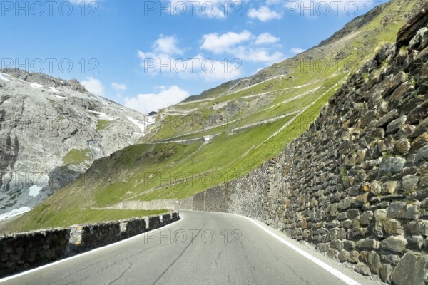 View of east ramp ascent to descent from Alpine pass Stelvio Stilfserjoch mountain road above tree line, right retaining wall wall of quarry stones, centre in the background many hairpin bends lead to pass summit of 2757 2758 metres high pass road mountain pass with tight bends hairpin bends Stilfser Joch Stelvio Stelvio, Stilfs, South Tyrol, Alto Adige, Italy