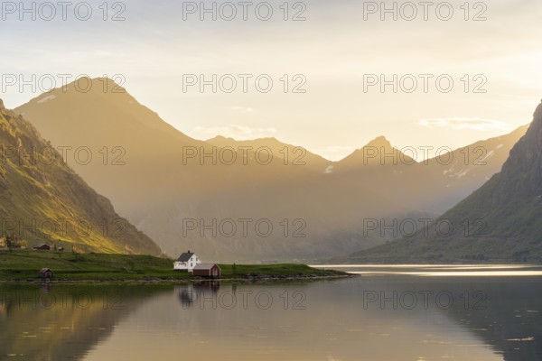 Landscape with sea and mountains on the Lofoten Islands. The fjord Flakstadpollen and some houses belonging to the village of Flakstad. At night during the midnight sun. Flakstadoya, Lofoten, Norway