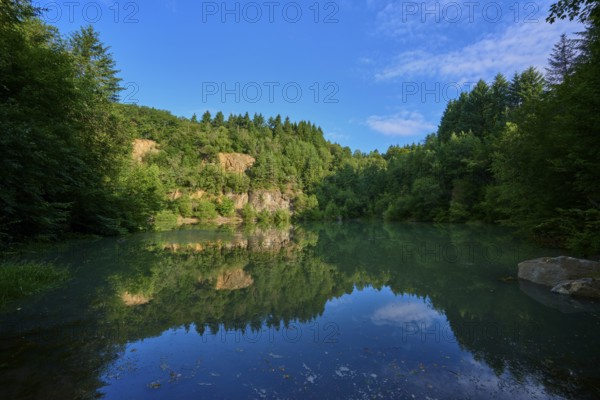 Tranquil lake in the middle of a forest with a clear water surface that reflects the sky, Katzenbuckelsee, Katzenbuckel, Waldbrunn, Neckar-Odenwald-Kreis, Odenwald, Baden-Württemberg, Germany