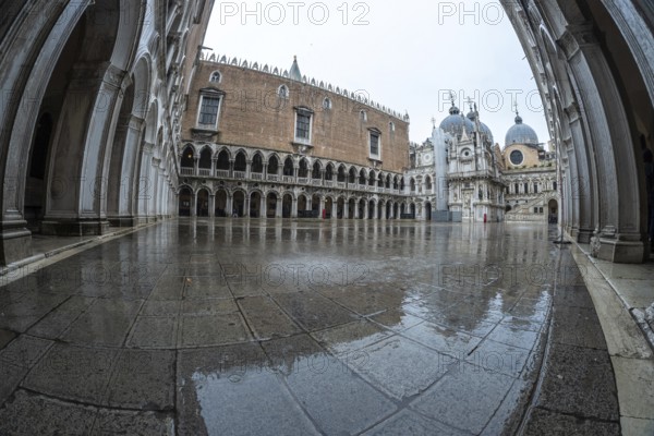 The doge's palace courtyard glistens with rainwater on a cloudy day in venice, italy, showcasing the historical architecture