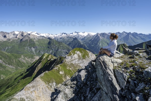 Mountaineer sitting on a rock in front of a mountain panorama with Großvenediger, mountain landscape with mountain peaks of the Venediger group, view from the summit of the Gösleswand, Lasörling group, Hohe Tauern National Park, East Tyrol, Tyrol, Austria