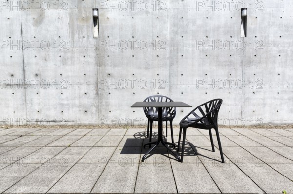 Black table and two plastic chairs in the courtyard made of exposed concrete, architect Tadao Ando, design, conference pavilion, conference building, Vitra Campus, Vitra Design Museum, Weil am Rhein, Baden-Württemberg, Germany