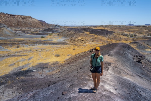 Tourist, Dry landscape with yellow grass and black volcanic hills, Burnt Mountain, Damaraland, Kunene, Namibia