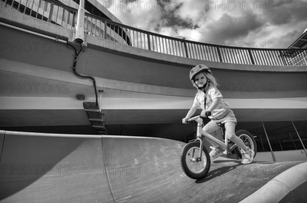 Girl, blonde, 3 years, laughing, riding with bicycle, bike, crash helmet, subway, urban, concrete, black and white, Stuttgart, Baden-Württemberg, Germany