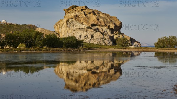 Large rock formation calmly reflected on the surface of the water, surrounded by nature, Kalikatsou Rocks, Seasonal Salt Lake, Grikos, Patmos, Dodecanese, Greek Islands, Greece