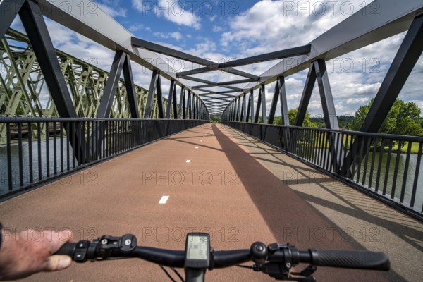 Ride over the De Massover cycle path bridge, over the Meuse south of Nijmegen, near Cuijk, part of the MaasWaalpad long-distance cycle path, 12 km between Nijmegen and Cuijk, built in 2021, for 15 million euros, Meuse river crossing for cyclists and pedestrians, part of a cycle path network, used by many commuters, next to a railway bridge, Netherlands