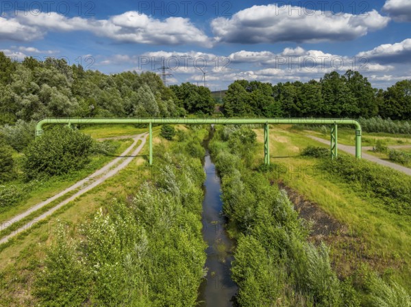 Bottrop, North Rhine-Westphalia, Germany - Renaturalised Boye, the tributary of the Emscher, has been transformed into a near-natural watercourse, flood protection through newly designed flooding areas, the Boye is now free of wastewater following the construction of a parallel sewer, is part of the Emscher river system and thus part of the Emscher conversion, was previously an open, above-ground wastewater channel, mixed water channel with surface water and wastewater. Wind turbine on the Mottbruch spoil tip at the back