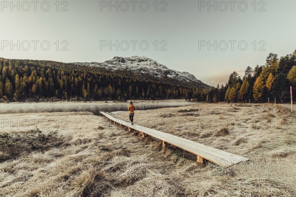 Young woman at Lake Staz near Sankt Moritz in the Engadine in Switzerland. Morning atmosphere with fog in autumn. Reflection of water