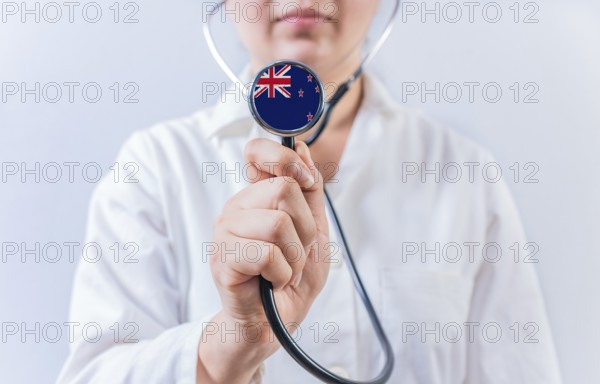 Female doctor holding stethoscope with New Zealand flag. National health system of New Zealand