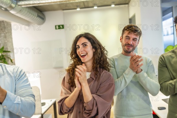 Group of smiling businesspeople applauding during a meeting in a modern office, celebrating success and teamwork
