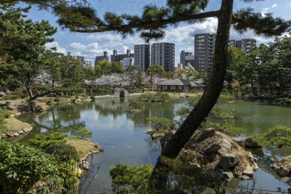 Shukkei-en with Sekisui-gan stone formation, green plants, trees and Koko-kyo stone bridge over Takuei-chi pond in spring, historical Japanese strolling garden, Japanese garden, green area, tourist attraction, sight, Naka-ku, Hiroshima, Japan