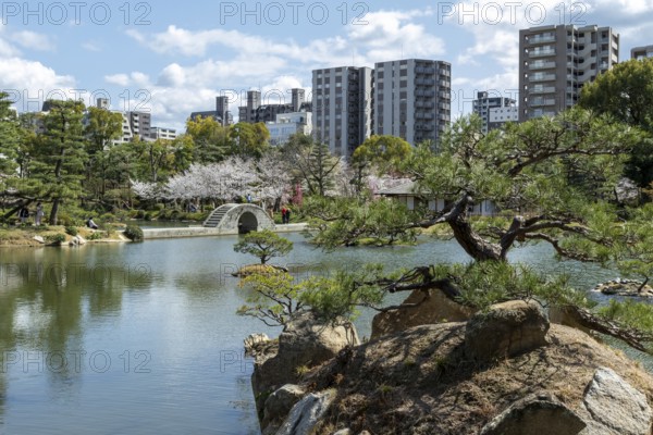 Shukkei-en with Sekisui-gan stone formation, green plants, trees and Koko-kyo stone bridge over Takuei-chi pond in spring, historical Japanese strolling garden, Japanese garden, green area, tourist attraction, sight, Naka-ku, Hiroshima, Japan