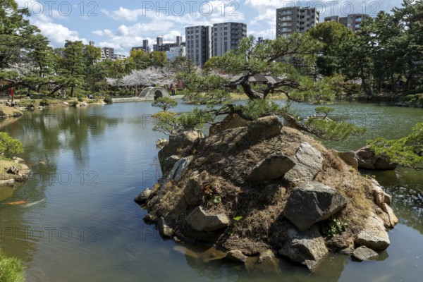 Shukkei-en with Sekisui-gan stone formation, green plants, trees and Koko-kyo stone bridge over Takuei-chi pond in spring, historical Japanese strolling garden, Japanese garden, green area, tourist attraction, sight, Naka-ku, Hiroshima, Japan