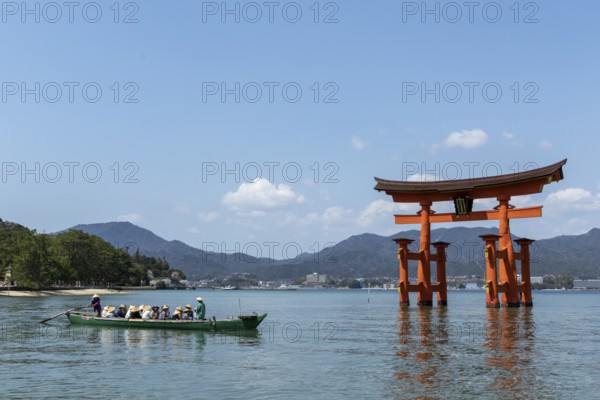 An excursion boat with tourists passes through the torii in the water, sight, tourist attraction, UNESCO World Heritage Site, Itsukushima Shrine, Miyajima Island, Hatsukaichi, Hiroshima Prefecture, Japan