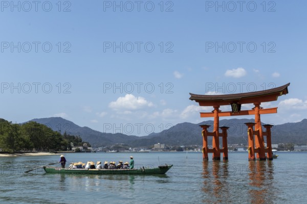 An excursion boat with tourists passes through the torii in the water, sight, tourist attraction, UNESCO World Heritage Site, Itsukushima Shrine, Miyajima Island, Hatsukaichi, Hiroshima Prefecture, Japan