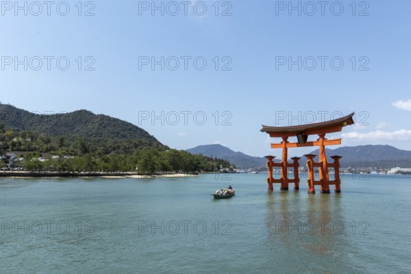 An excursion boat with tourists passes through the torii in the water, sight, tourist attraction, UNESCO World Heritage Site, Itsukushima Shrine, Miyajima Island, Hatsukaichi, Hiroshima Prefecture, Japan