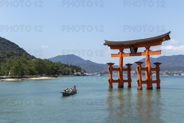 An excursion boat with tourists passes through the torii in the water, sight, tourist attraction, UNESCO World Heritage Site, Itsukushima Shrine, Miyajima Island, Hatsukaichi, Hiroshima Prefecture, Japan