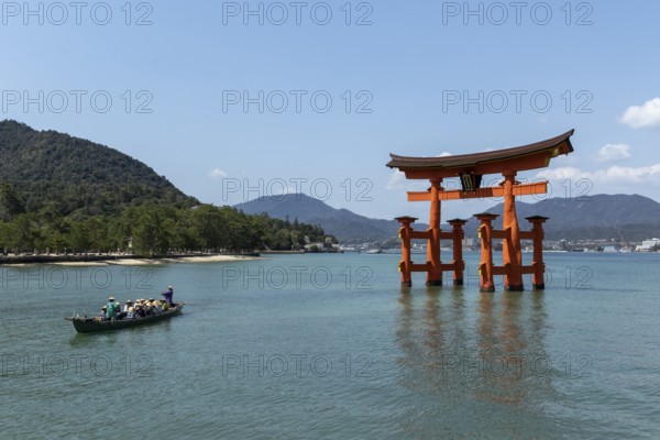 An excursion boat with tourists passes through the torii in the water, sight, tourist attraction, UNESCO World Heritage Site, Itsukushima Shrine, Miyajima Island, Hatsukaichi, Hiroshima Prefecture, Japan