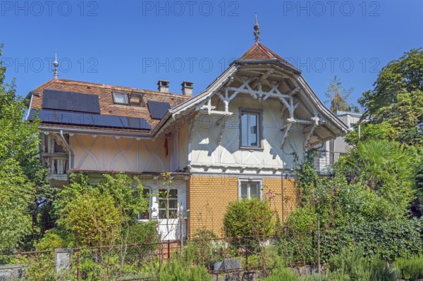 Interesting roof truss of a villa from around 1900, tiled roof with solar panels and a somewhat overgrown garden, Dornbirn, Vorarlberg, Austria
