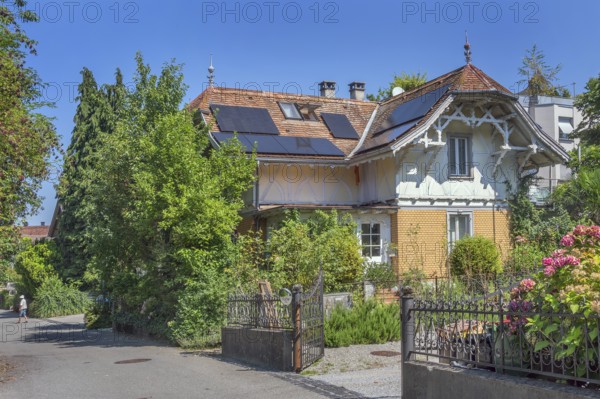 Interesting roof truss of a villa from around 1900, tiled roof with solar panels and a somewhat overgrown garden, Dornbirn, Vorarlberg, Austria