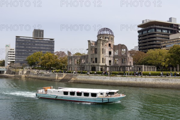 Excursion boat and ruins of the Atomic Bomb Dome, tourist attraction, UNESCO World Heritage Site, peace memorial and memorial to the victims of the atomic bombing of Hiroshima in the Peace Park on the Otagawa River, Naka Ward, Hiroshima, Japan