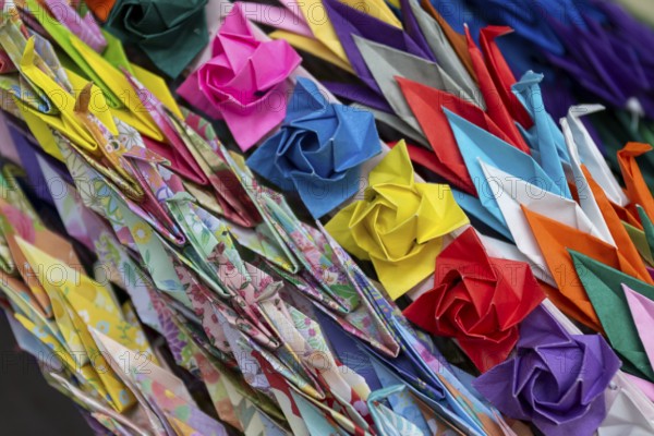 Chains of colourful origami cranes made of paper as a sign of peace in the Peace Park, close-up, background image, landmark, UNESCO World Heritage Site, peace memorial and memorial to the victims of the atomic bombing of Hiroshima, Naka Ward, Hiroshima, Japan