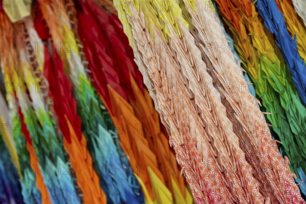 Chains of colourful origami cranes made of paper as a sign of peace in the Peace Park, close-up, background image, landmark, UNESCO World Heritage Site, peace memorial and memorial to the victims of the atomic bombing of Hiroshima, Naka Ward, Hiroshima, Japan
