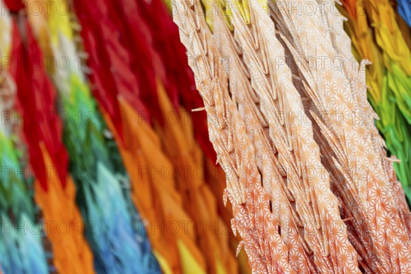 Chains of colourful origami cranes made of paper as a sign of peace in the Peace Park, close-up, background image, landmark, UNESCO World Heritage Site, peace memorial and memorial to the victims of the atomic bombing of Hiroshima, Naka Ward, Hiroshima, Japan