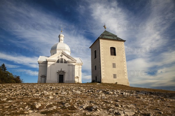 White church and tower in an open landscape under a blue sky with clouds, Mikulov Nikolsburg Czech Republic