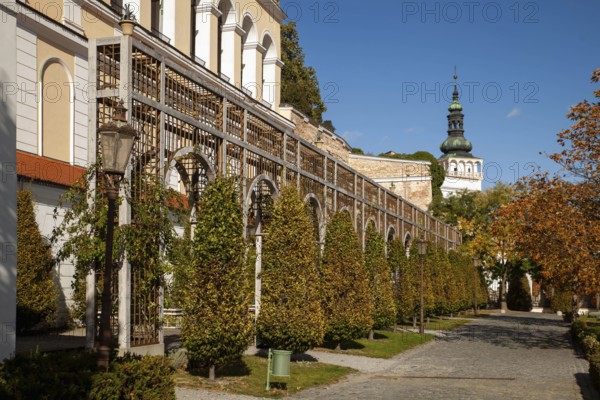 A well-tended garden with trees and antique lanterns in front of a series of arches, Mikulov Nikolsburg Czech Republic