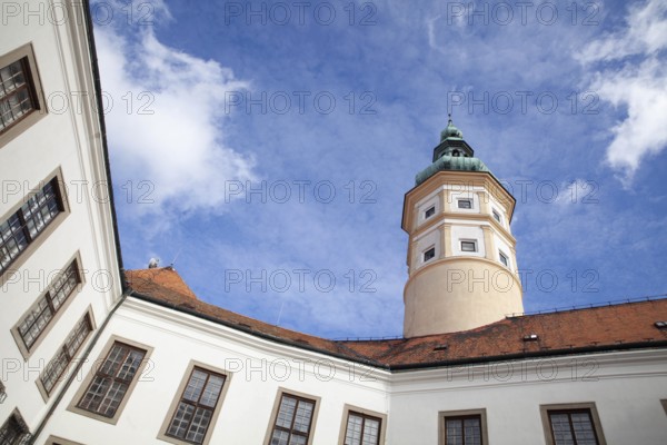 A historic tower rises under a clear blue sky, surrounded by buildings with red tiled roofs, Mikulov Nikolsburg Czech Republic