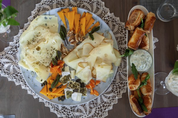 A cheese platter with different types of cheese and dumplings, decorated with herbs on a wooden table, Lower Austria Austria