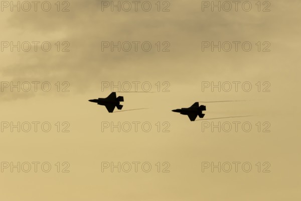 Lockheed Martin F-35 Lightning II fighter two military aircraft of the United States air force USAF silhouette in flight at sunset at RAF Lakenheath airbase, Suffolk, England, United Kingdom