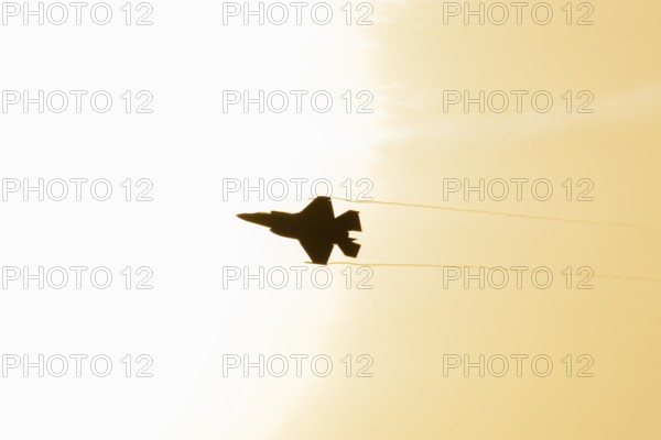 Lockheed Martin F-35 Lightning II fighter military aircraft of the United States air force USAF silhouette in flight at sunset at RAF Lakenheath airbase, Suffolk, England, United Kingdom